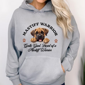 May include: A light gray hoodie with a front pocket and a drawstring. The hoodie features a circular graphic with a Mastiff puppy illustration and the text "MASTIFF WARRIOR" and "Gentle Giant, Heart of a Mastiff Warrior".