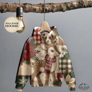 May include: A pullover hoodie featuring a festive patchwork design with a central reindeer wearing a red scarf, surrounded by poinsettia flowers, green pine branches, snowflakes, and red and black buffalo plaid patterns on a cream-coloured background.