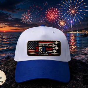May include: A white and blue baseball cap featuring a rectangular patch on the front. The patch displays the American flag, five fighter jets, and the text AMERICA'S 250 YEARS 1776-2026. The cap has a white crown and a solid blue brim.