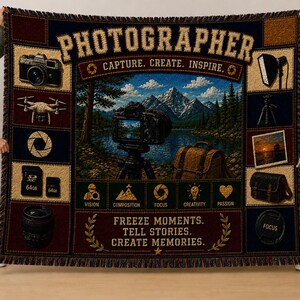 May include: A woven throw blanket featuring a central landscape scene with a camera on a tripod, surrounded by photography icons, equipment, and text including "PHOTOGRAPHER," "CAPTURE, CREATE, INSPIRE," and "FREEZE MOMENTS. TELL STORIES. CREATE MEMORIES."