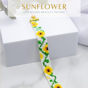 May include: A white beaded bracelet with a sunflower pattern. The bracelet is made with seed beads and has a gold clasp. The text "SUNFLOWER" and "SEED BEADED BRACELET PATTERN" is above the bracelet. The text "AWAKEN YOUR STYLE" is below the bracelet.