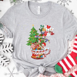 Camiseta navideña con personajes de Toy Story de Disney: Buzz Lightyear, Woody, Jessie, Slinky, Mickey y sus amigos, con luces de árboles de Navidad.