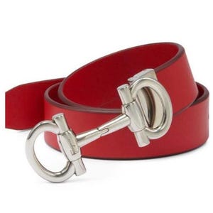 May include: A red leather belt with a silver buckle featuring a horseshoe design. The buckle has the word "Ferragamo" engraved on it.