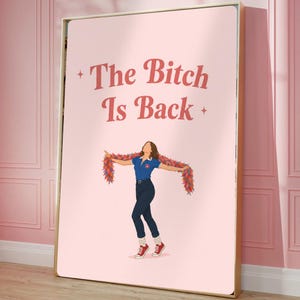 Może przedstawiać: Oprawiony wydruk artystyczny z napisem "The Bitch Is Back" w kolorze czerwonym. Grafika przedstawia kobietę w niebieskiej koszulce polo, ciemnych dżinsach i czerwonych trampkach, z kolorową boa. Tło jest jasnor&oacute;żowe.