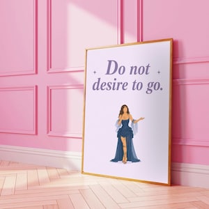 Puede incluir: Una impresión artística enmarcada con el texto "Do not desire to go." presenta una ilustración de una mujer con un vestido azul. La obra de arte está sobre un fondo blanco, enmarcada en dorado y apoyada contra una pared rosa.