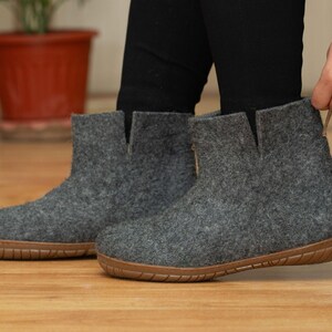 A pair of gray felt ankle boots with a brown rubber sole. The boots have a simple design and are made of a soft, comfortable material.