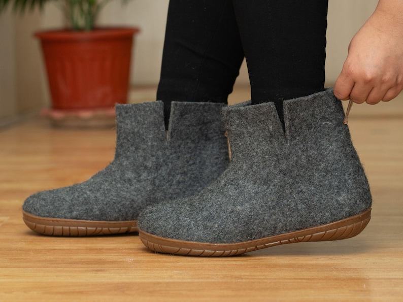 A pair of gray felt ankle boots with a brown rubber sole. The boots have a simple design and are made of a soft, comfortable material.