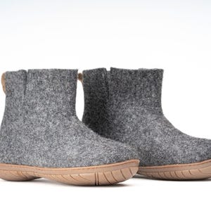 A pair of gray felt ankle boots with a brown rubber sole. The boots have pull tab on the back.
