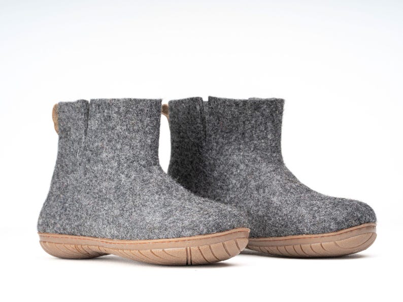 A pair of gray felt ankle boots with a brown rubber sole. The boots have pull tab on the back.
