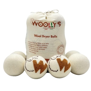 Peut inclure: Un ensemble de boules de séchage en laine blanc cassé, certaines avec des motifs bruns, et un sac à cordon. Le sac porte l'inscription "WOOLLY'S ITALIAN DESIGN" et "Wool Dryer Balls". Le texte mentionne la réduction du temps de séchage.