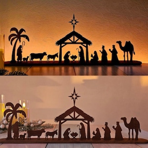 Op de afbeelding: Een houten silhouet van een kerststal. De scène omvat een palmboom, dieren, een stal met een ster en figuren die de heilige familie en de drie wijzen vertegenwoordigen. De figuren zijn allemaal donkerbruin.