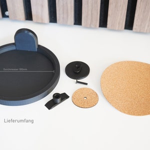 K&ouml;nnte beinhalten: Eine schwarze Plattentellermatte mit einem Durchmesser von 100 mm, eine schwarze Plattenteller-Slipmat, eine schwarze Plattenteller-Spindel, eine schwarze Schraube, eine schwarze Plattenteller-Klemme, eine Kork-Plattenteller-Slipmat und der Text "Durchmesser 100mm" und "Lieferumfang".