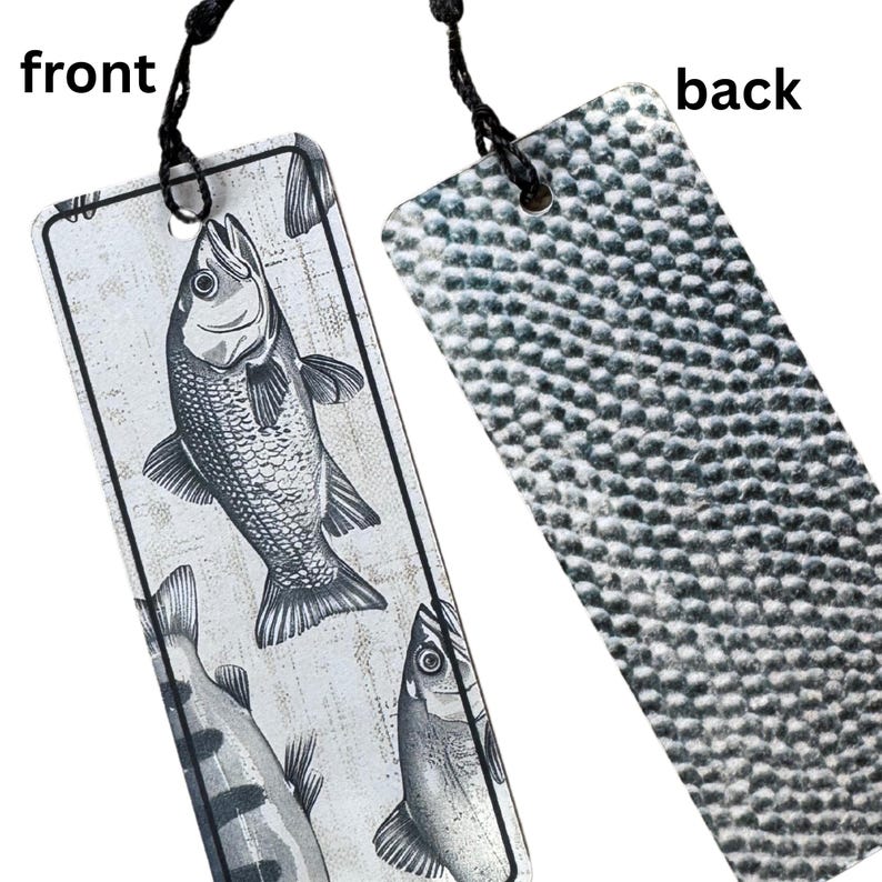 May include: A white bookmark with a black and white illustration of three fish. The back of the bookmark has a textured, gray surface.