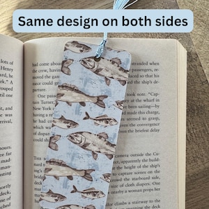 May include: A blue bookmark with a pattern of brown fish on a light blue background. The bookmark has a blue tassel.