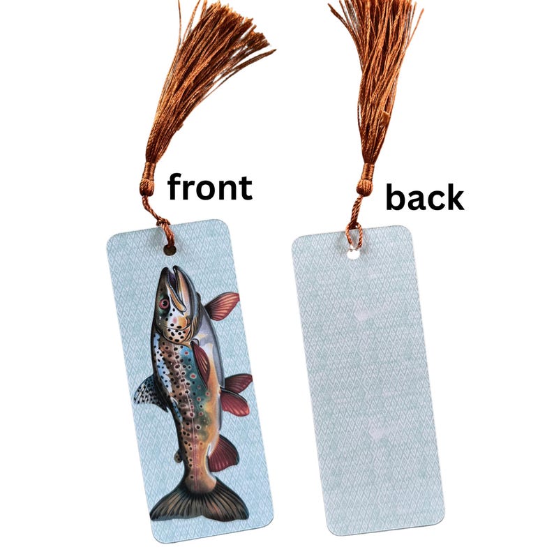 May include: A brown tassel bookmark with a trout illustration on the front and a blue patterned design on the back. The bookmark is made of sturdy cardstock.