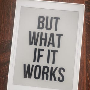 Op de afbeelding: Een witte e-reader met een zwart scherm waarop de tekst "BUT WHAT IF IT WORKS" staat.