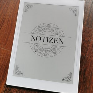 May include: A white e-reader with a black and white geometric design and the word "NOTIZEN" in the center of the screen.