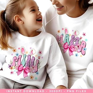May include: Two white shirts with a bunny design. One shirt says "Mama" in pastel colors with a pink bow and the other says "Mini" in pastel colors with a pink bow.