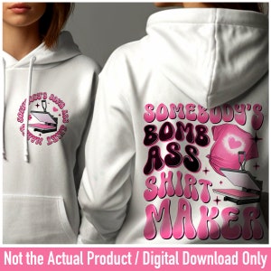 May include: White hoodie with a pink graphic design that says "Somebody's Bomb Ass Shirt Maker" with a heat press and a t-shirt.