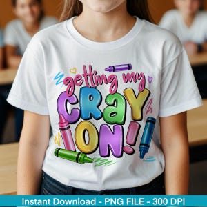 May include: White t-shirt with a colourful graphic that says "Getting my Crayon On!" with crayons around the text.