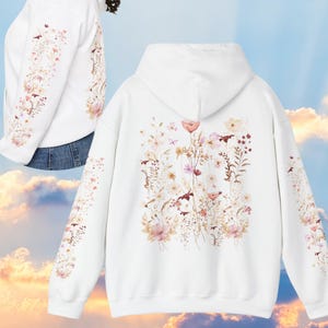 Pu&ograve; includere: Felpa con cappuccio bianca con stampa floreale sul retro e sulle maniche. I fiori sono in tonalit&agrave; di rosa, marrone e bianco.