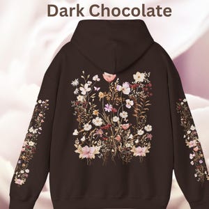 Pu&ograve; includere: Felpa con cappuccio marrone cioccolato scuro con una stampa floreale che presenta una variet&agrave; di fiori e foglie in tonalit&agrave; di rosa, bianco e marrone.