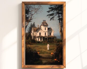 May include: A framed print of a white Victorian house with a person in a white robe walking on the lawn. The artwork is set in a landscape with trees and pumpkins, evoking a spooky, autumnal theme. The frame is made of wood.