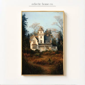 May include: A framed print of a white Victorian house with a tower, surrounded by trees and foliage. The artwork has a vintage aesthetic, with a gold frame and the text "eclectic home co." at the top.