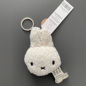 May include: A cream-coloured plush bunny keyring with a silver metal ring. The bunny has black eyes and a cross-shaped mouth. A tag with "BON TON TOYS" and a bunny illustration is attached.