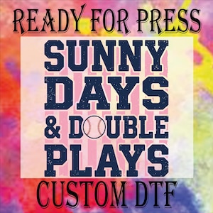 May include: A colorful graphic design with the text "READY FOR PRESS" at the top and "SUNNY DAYS & DOUBLE PLAYS" with a baseball in the center. The bottom text reads "CUSTOM DTF". The background has a watercolor effect.