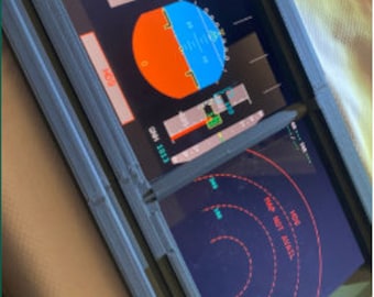 May include: A 3D printed frame with two screens displaying a circular gauge with red, orange, and blue sections, and a vertical gauge with a red needle. The text "HOG" and "PAP HOT AVAIL" is visible on the screens.