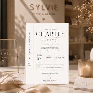 May include: A white rectangular charity event invitation card featuring black and gold serif typography. The text includes details for a gala on Saturday, September 27, 2025, at The Ivy Room in Dallas, Texas, with a vertical side border.