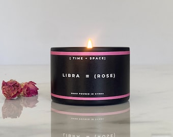 May include: Black candle with a pink band and white text that reads "[TIME + SPACE] LIBRA = (ROSE)" and "HAND POURED IN CYMRU".