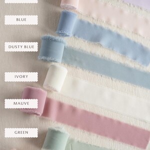 May include: Seven spools of frayed-edge ribbon in various colours, labelled as Lilac, Blush Pink, Blue, Dusty Blue, Ivory, Mauve, Green, and Rose. Each spool is rolled with a textured fabric finish, displaying a soft, matte appearance.