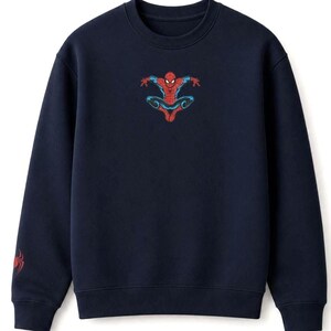 May include: Navy blue sweatshirt featuring a red and blue Spider-Man graphic on the chest. A smaller Spider-Man logo is on the left sleeve. The crew neck sweatshirt is made of a soft material.
