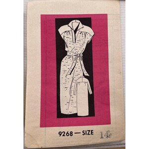 Może przedstawiać: Wzór krawiecki w stylu vintage przedstawiający projekt sukienki z kołnierzem, krótkimi rękawami i paskiem w talii. Czarno-biała ilustracja umieszczona jest na czarnym tle w różowym prostokącie. Numer wzoru 9268, rozmiar 14.