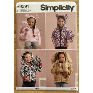 May include: Simplicity sewing pattern S9391 featuring children's hooded jackets with animal ear details. The jackets include a pink bunny, a pink leopard, a black and white dalmatian, and a brown bunny. The pattern is designed and printed in the USA.