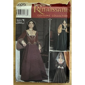 May include: A Simplicity Renaissance Costume Collection sewing pattern envelope 9929 featuring Andrea Schewe designs. The package displays three variations of long, floor-length dresses with fitted bodices, long sleeves, and headpieces.