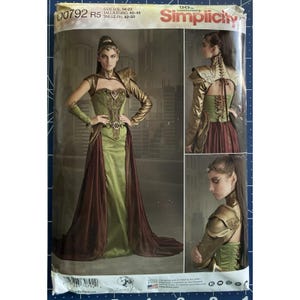 May include: Simplicity sewing pattern featuring a fantasy-themed gown with gold accents, a corset-style bodice, and a flowing skirt. The pattern includes multiple views of the design, showcasing the dress from different angles. The pattern number is 00792.