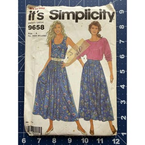 Puede incluir: Patrón de costura Simplicity 9658 con dos conjuntos de mujer. El patrón incluye un vestido azul con estampado floral y un top rosa con una falda floral azul. El patrón es de la talla A, todas las tallas están incluidas.