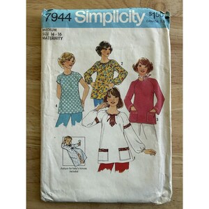 May include: A vintage Simplicity sewing pattern for maternity tops and a baby kimono. The pattern features illustrations of various top designs, including a floral print and a top with pockets. The size is medium, for sizes 14-16.