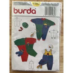 Puede incluir: Un paquete de patrones de costura Burda con diseños de ropa infantil. El paquete incluye ilustraciones de monos, sombreros y accesorios coloridos. El logotipo de Burda aparece en la parte superior, con información de tallas y un código de barras.