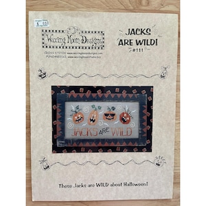 May include: A craft pattern titled "Jacks Are Wild!" featuring a cross-stitch design of four jack-o'-lanterns. The design is framed with a black border and the text "Jacks Are Wild" is below the pumpkins. The pattern is for Halloween.