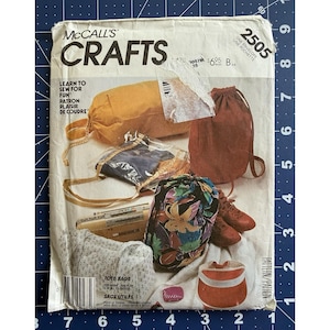 May include: A McCall's Crafts 2505 sewing pattern envelope featuring illustrations of various bags including a mustard yellow duffel, a brown drawstring backpack, a floral print pouch, a quilted tote, and a red visor, with text Learn to Sew for Fun.