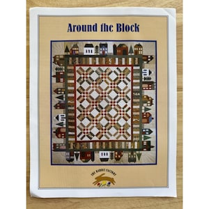 May include: A printed pattern for a quilt titled "Around the Block." The design features a central patchwork pattern surrounded by a border of stylized houses and buildings in various colors. The Rabbit Factory logo is at the bottom.