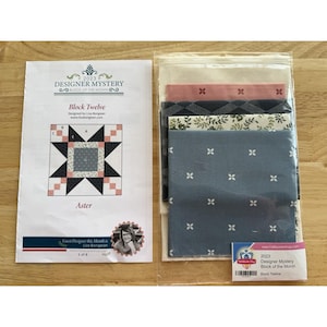 May include: A quilting kit with a printed pattern and fabric squares. The pattern is titled "Designer Mystery Block of the Month" and features a star design. The fabric squares are in shades of blue, pink, and white, with floral and geometric patterns.