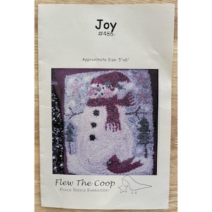 May include: A punch needle embroidery kit featuring a snowman design. The kit includes a snowman with a red scarf and hat, set against a snowy background. The package is labeled "Joy" and "#486", with an approximate size of 5"x6". The brand is "Flew The Coop".