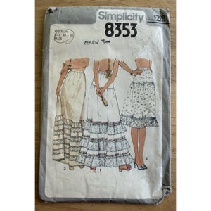 Puede incluir: Un sobre de patrón de costura Simplicity 8353 para talla mediana 14-16. El frente presenta ilustraciones de tres variaciones de falda: una falda larga con encaje, una falda con volantes escalonados y una falda estampada con dobladillo.