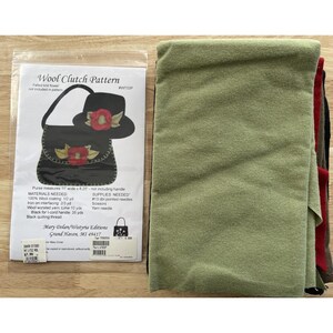 May include: A craft kit featuring a "Wool Clutch Pattern" with a felted knit flower design. The kit includes a pattern, and green, red, and black wool fabric. The purse measures 11 inches wide by 8.25 inches.