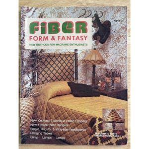 May include: A vintage book cover titled "Fiber Form & Fantasy" with text in green and red. The cover features a bedroom scene with a bed, lamps, and macrame accents. Additional text includes "New Methods for Macrame Enthusiasts."